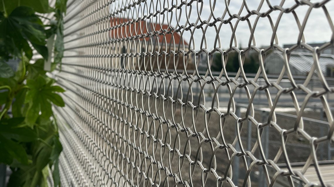 Rede em espiral de aço inoxidável na parte da frente de uma escada exterior. A malha metálica foi feita por medida para revestir as escadas deste edifício 206 Lafayette HQ. Projetado por Think Tank Architecture.  - <p>Para o projeto QG 206 Lafayette, a rede em espiral de aço inoxidável Torroja F foi selecionada pela Think Tank Architecture e fabricada à medida para ser utilizada como revestimento de escadas exteriores e como enchimento de vedações com uma estrutura metálica branca assente num deck de madeira exterior. Para mais informações, contacte-nos <a href=